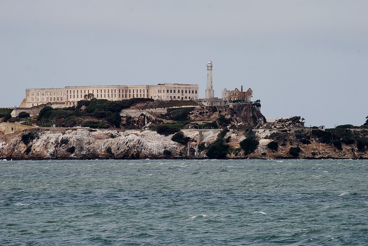 Alcatraz from the water: the cellhouse along the top of the rock and the lighthouse beside it