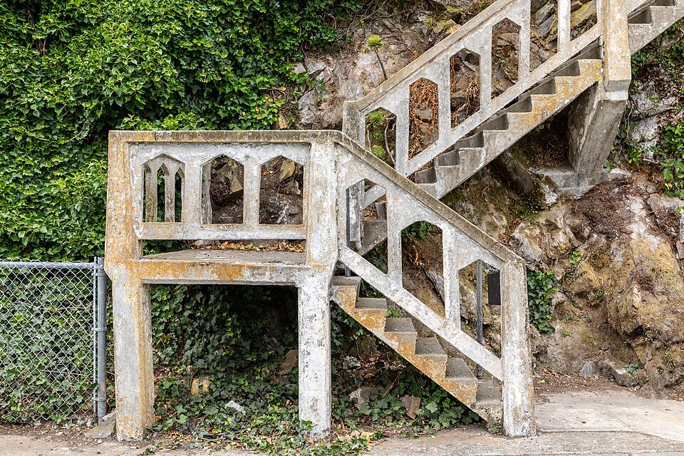A weathered concrete stairway climbing the overgrown slope on Alcatraz