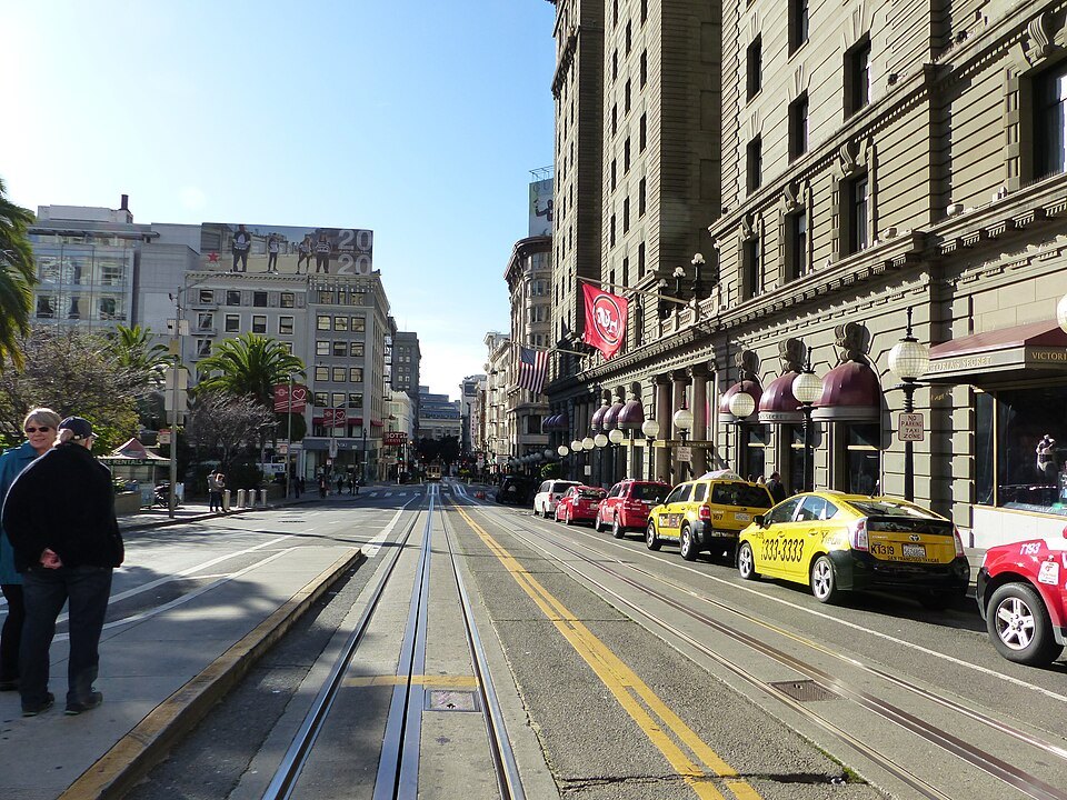 The tracks up Powell Street past the hotels at Union Square, taxis lined along the curb