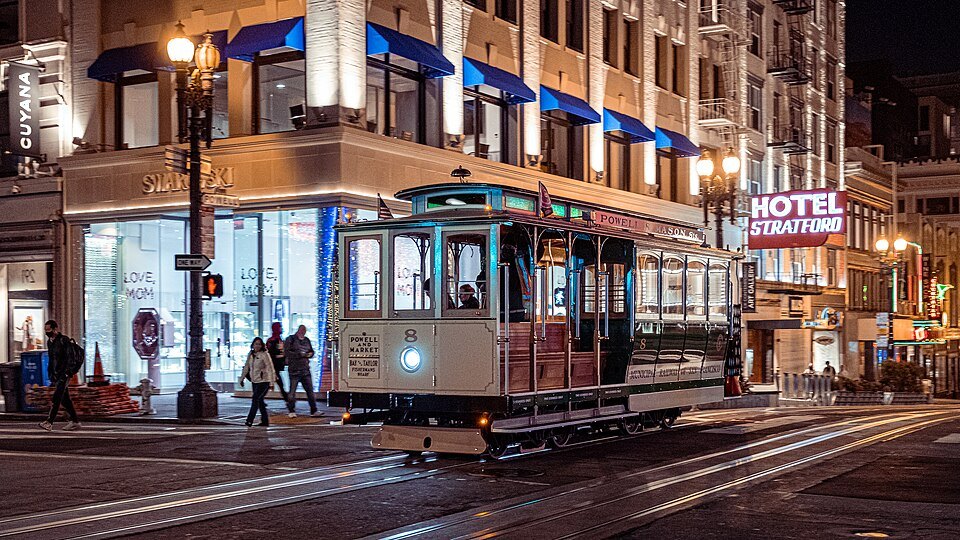 A cable car crossing Powell Street by the Hotel Stratford at night