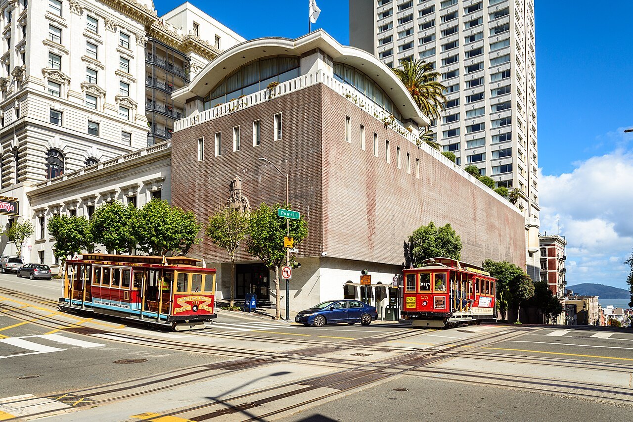 Two cable cars on Powell Street at Nob Hill, passing a red-brick building