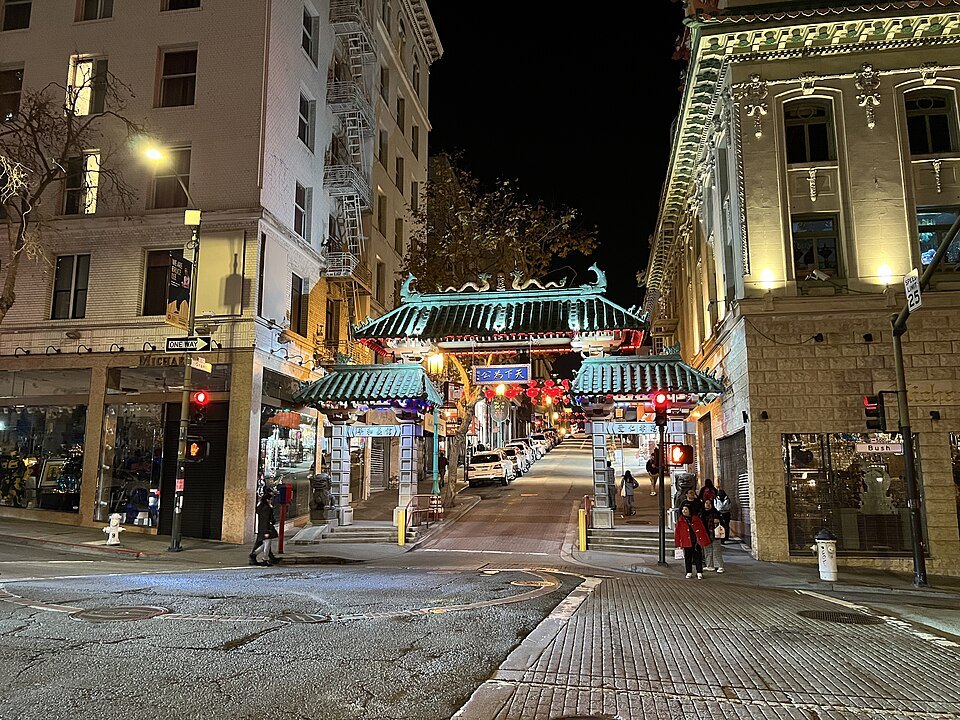 The Dragon Gate lit up at night, Grant Avenue running uphill behind it