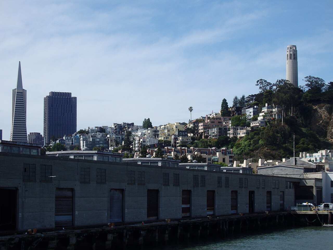 Coit Tower on Telegraph Hill above the piers, the Transamerica Pyramid to the left