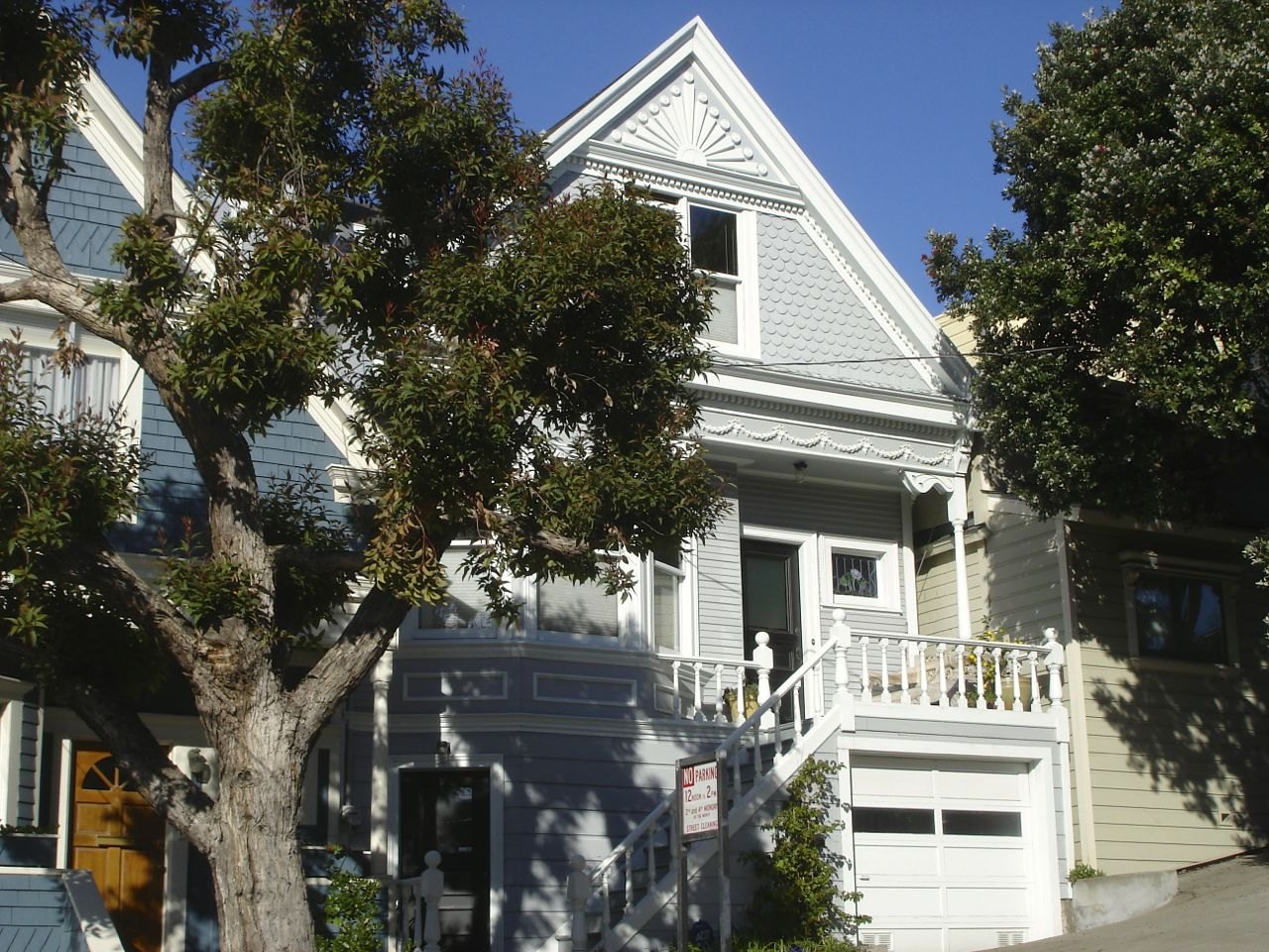 A gray gabled Victorian house behind a tree in Noe Valley