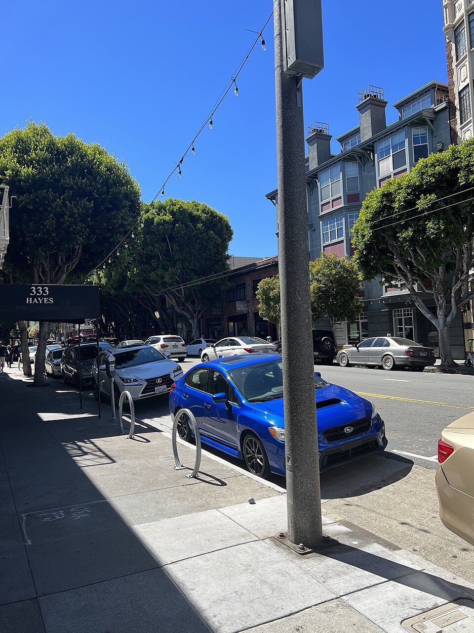 A sidewalk in Hayes Valley, cars parked under the trees
