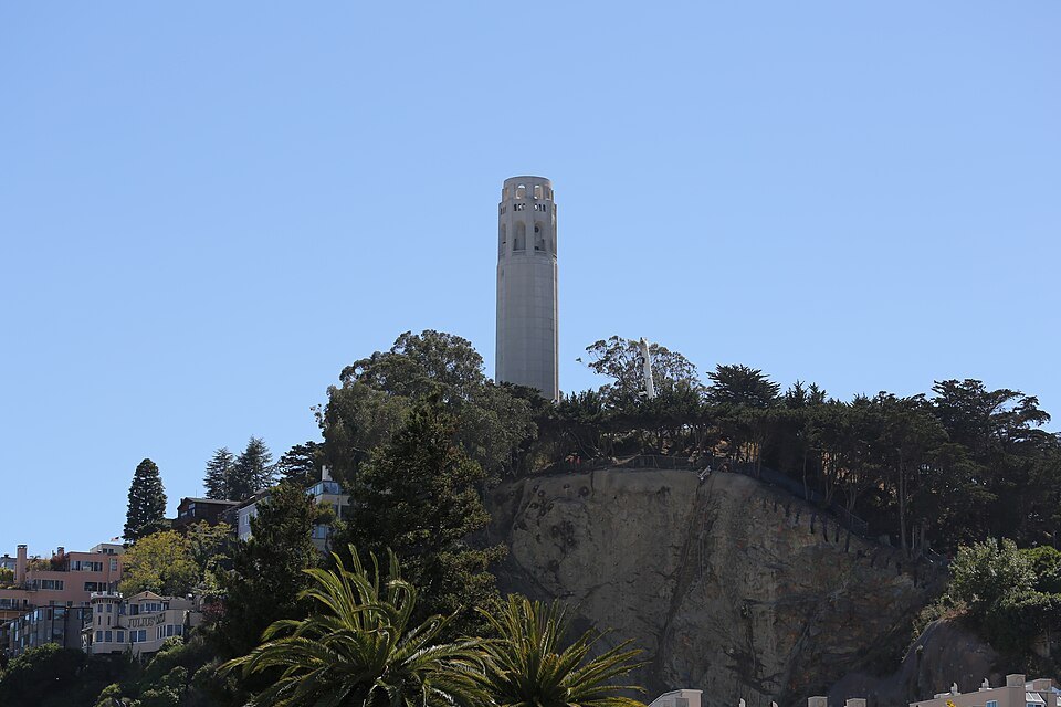 Coit Tower above the trees and cliffs of Telegraph Hill, seen from the waterfront