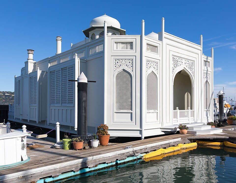 A white houseboat with domes and arched windows, moored in Sausalito