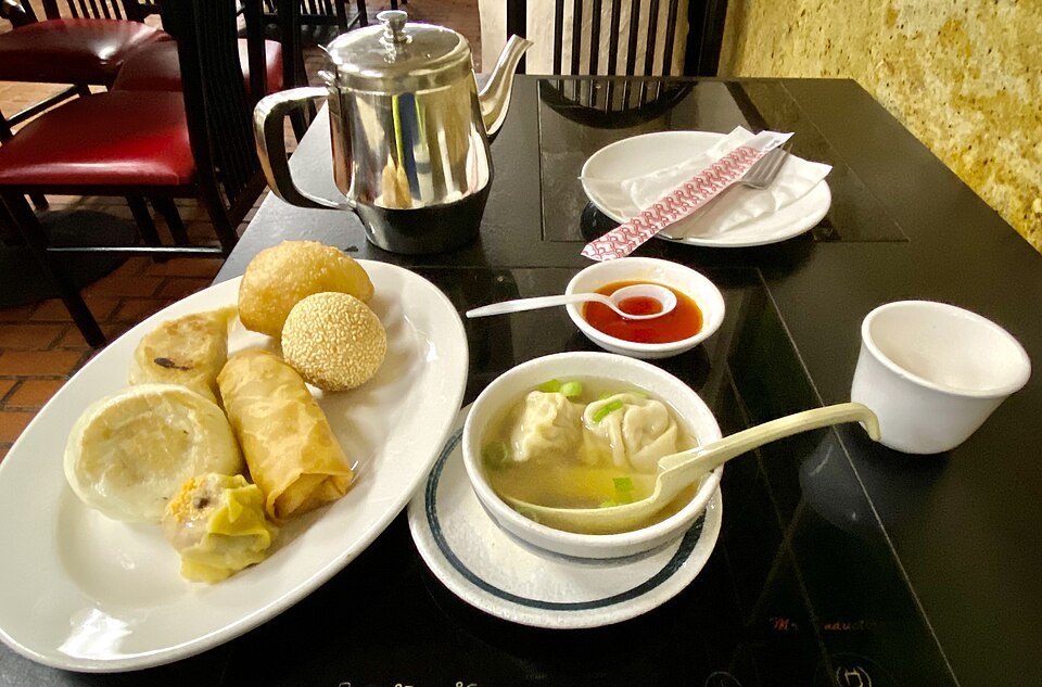 Dim sum at a Chinatown table: buns, rolls, dumplings in soup and tea