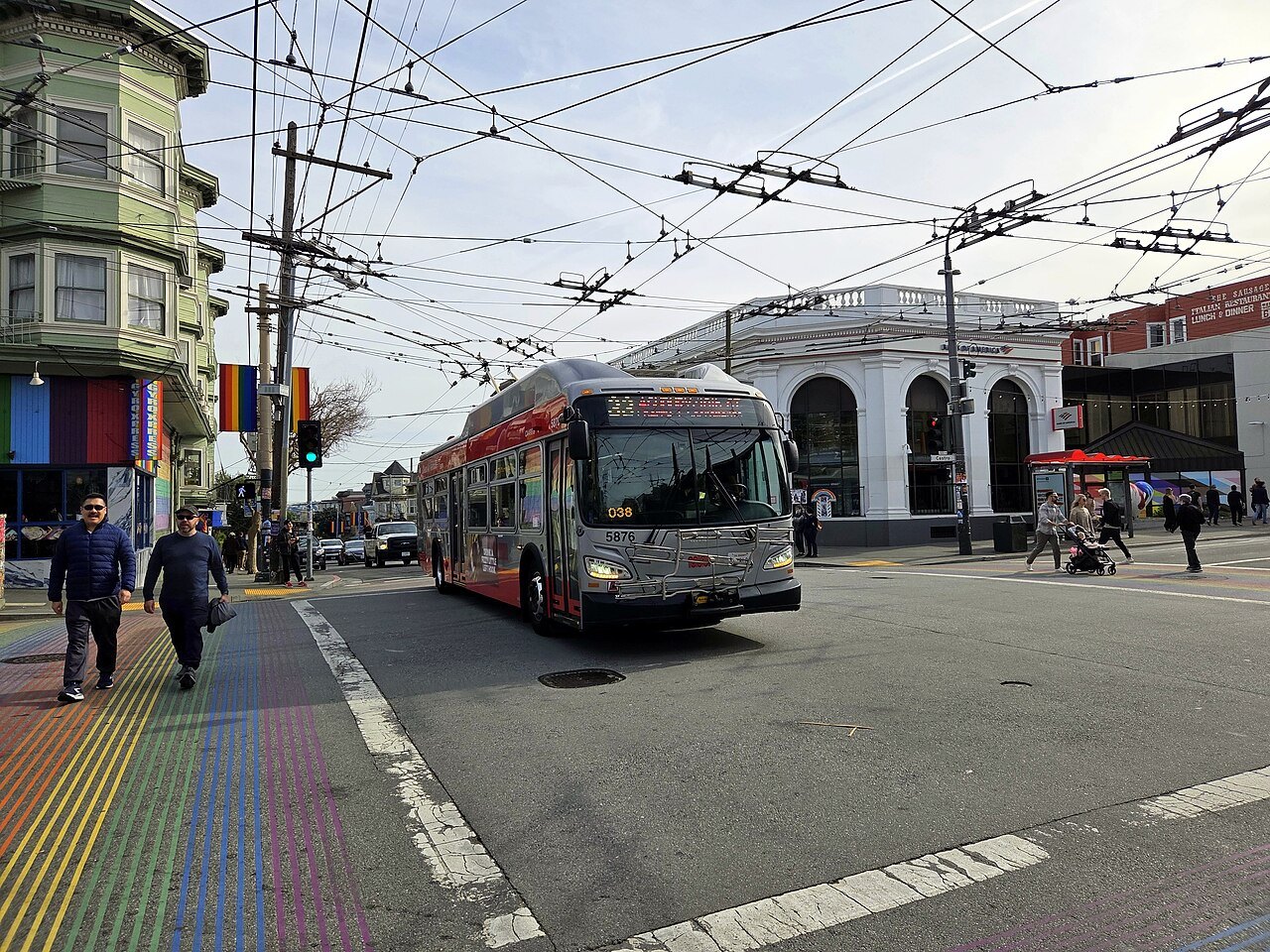 A trolleybus crossing Castro Street by the rainbow crosswalk