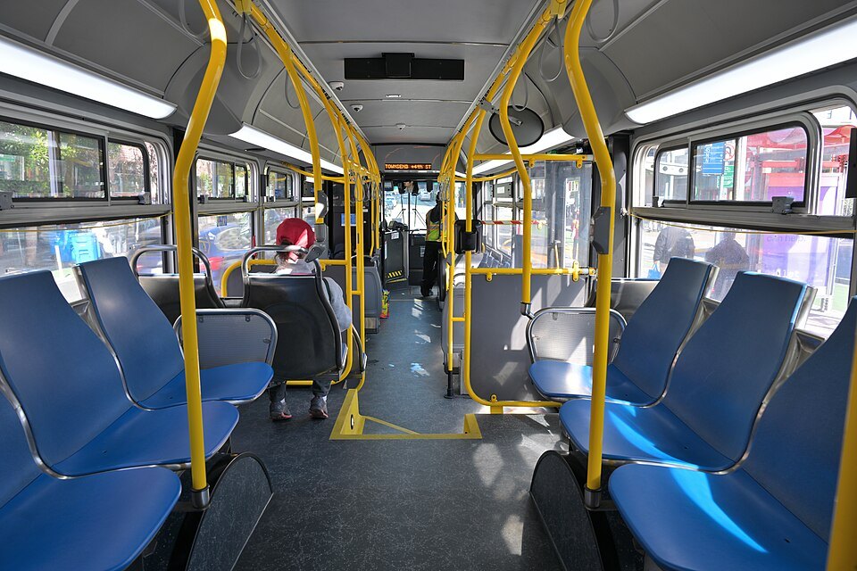 Inside an electric trolleybus: blue seats and yellow grab rails