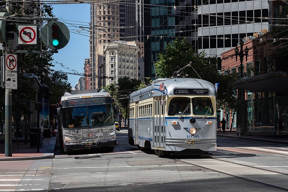 A heritage streetcar and a bus side by side on the Embarcadero