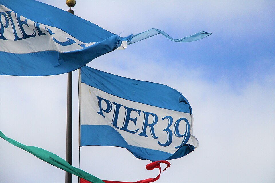Blue-and-white Pier 39 flags snapping in the wind