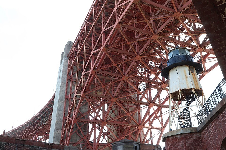 The lighthouse on Fort Point's roof, under the red steel arch of the bridge