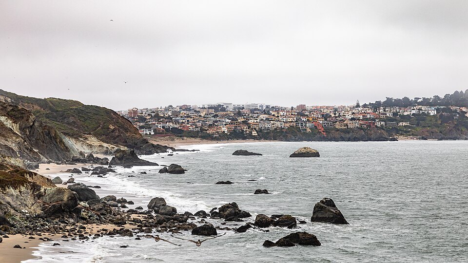 Rocks and surf below the cliffs at Baker Beach, the Sea Cliff houses beyond