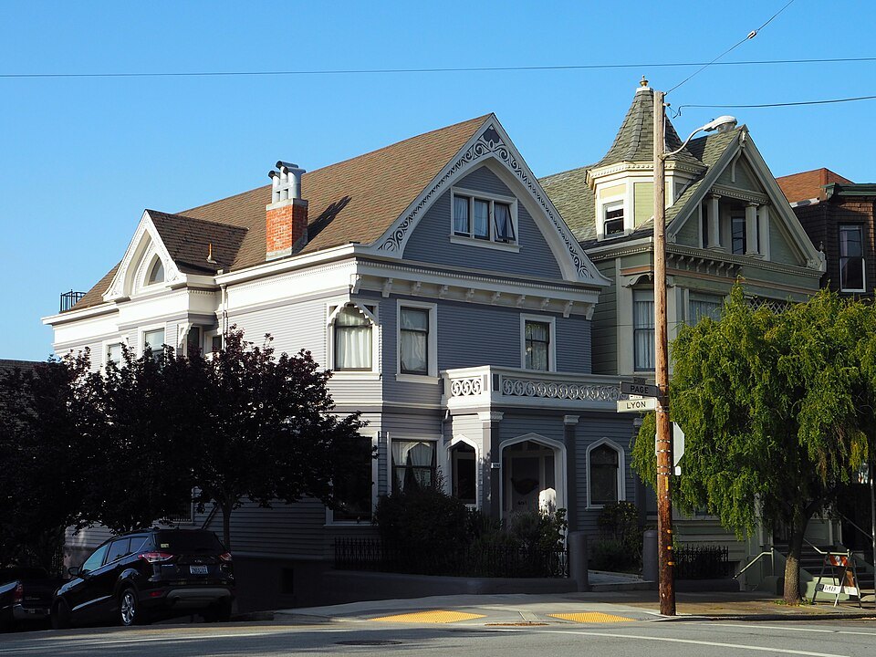 A gray gabled Victorian house behind its garden in the Haight