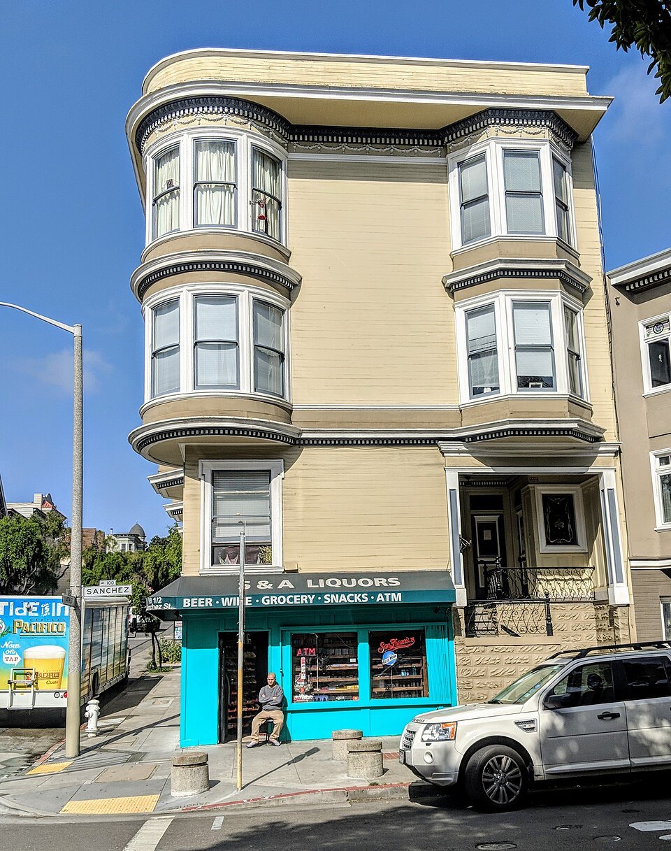 A cream Victorian corner building with round bays over a small shop