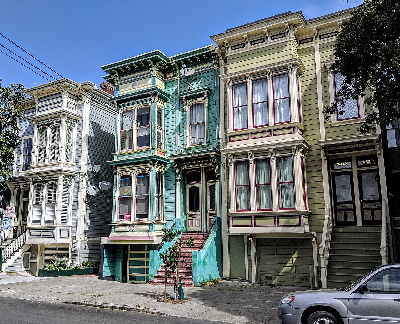 Three painted Victorians side by side with their bay windows and front steps