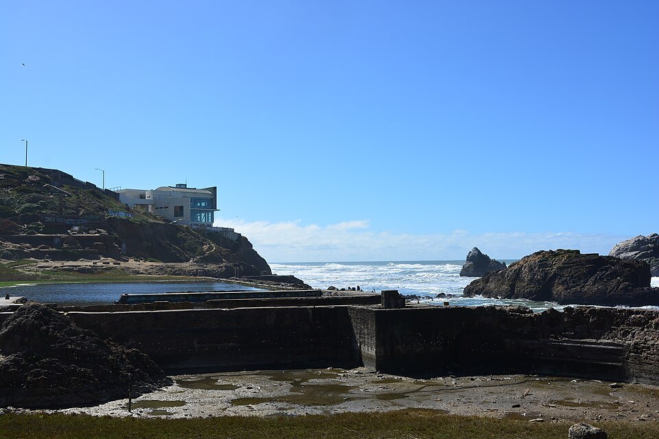 The concrete walls of the Sutro Baths ruins, the cliff-top building beyond
