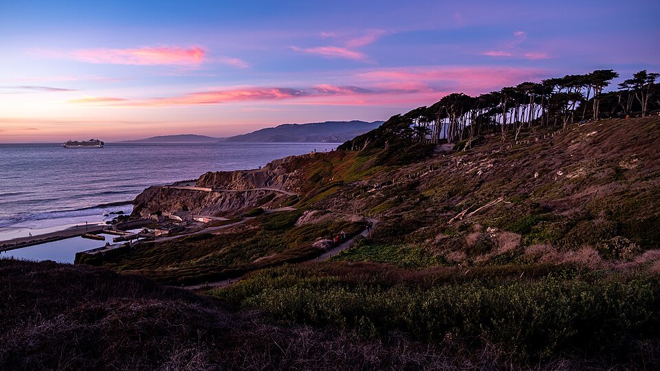 The cypress-topped cliffs of Lands End at dusk, the Golden Gate beyond