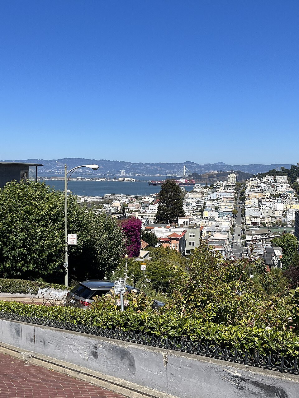 The top of Lombard Street's crooked block, the bay and Russian Hill beyond