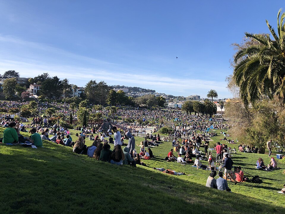 A crowd on the sunny slope of Mission Dolores Park