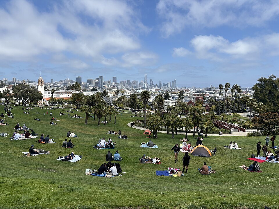 Picnickers across the lawns of Mission Dolores Park, downtown on the horizon