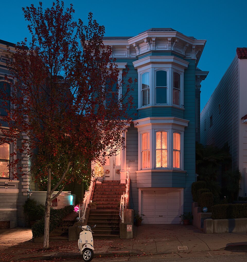 A bay-windowed Victorian lit at dusk on Washington Street