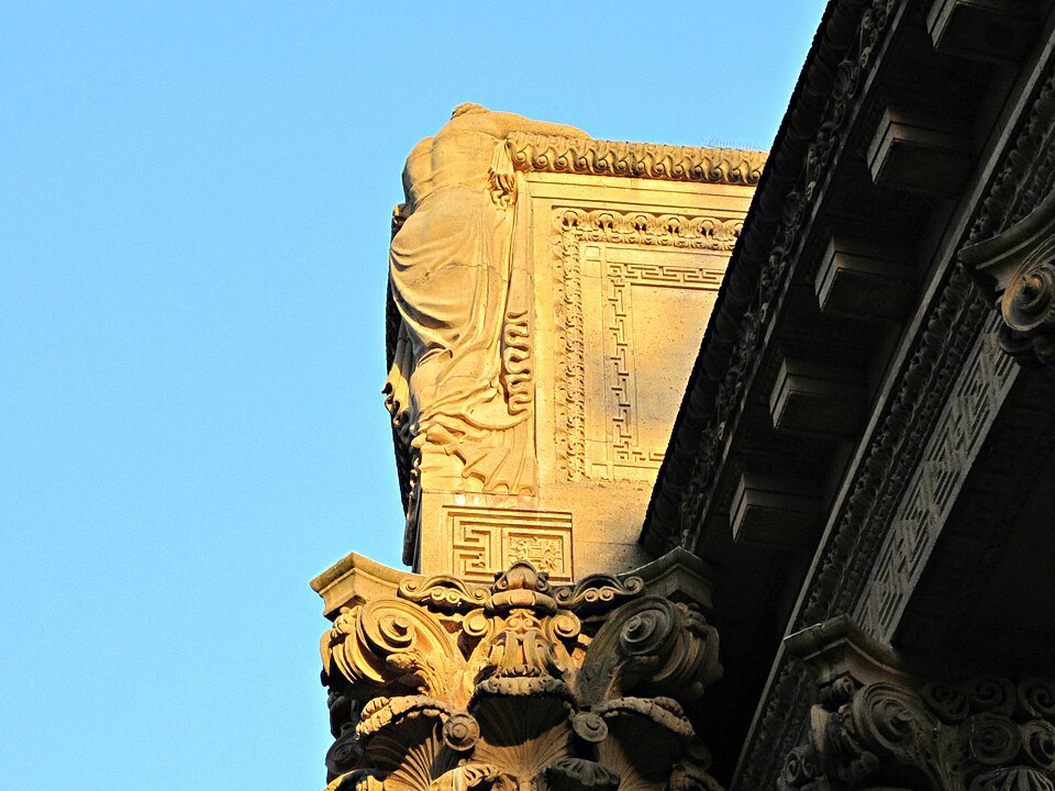 A carved figure leaning over a column's capital at the Palace of Fine Arts