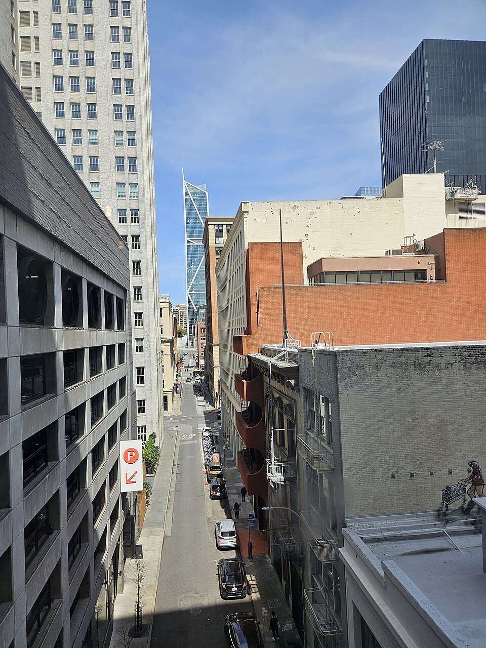 A narrow SoMa alley below the museum's walls and the towers beyond